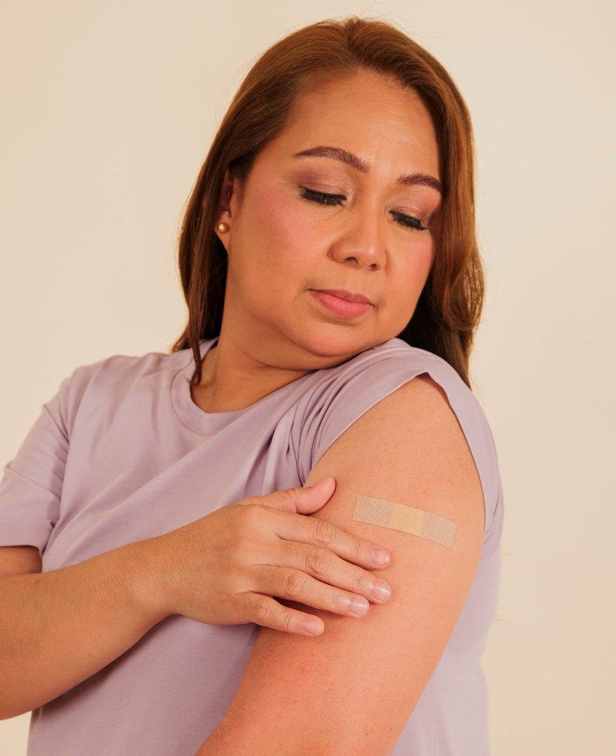 A Kindred patient looking down at the plaster on her arm after her vaccination
