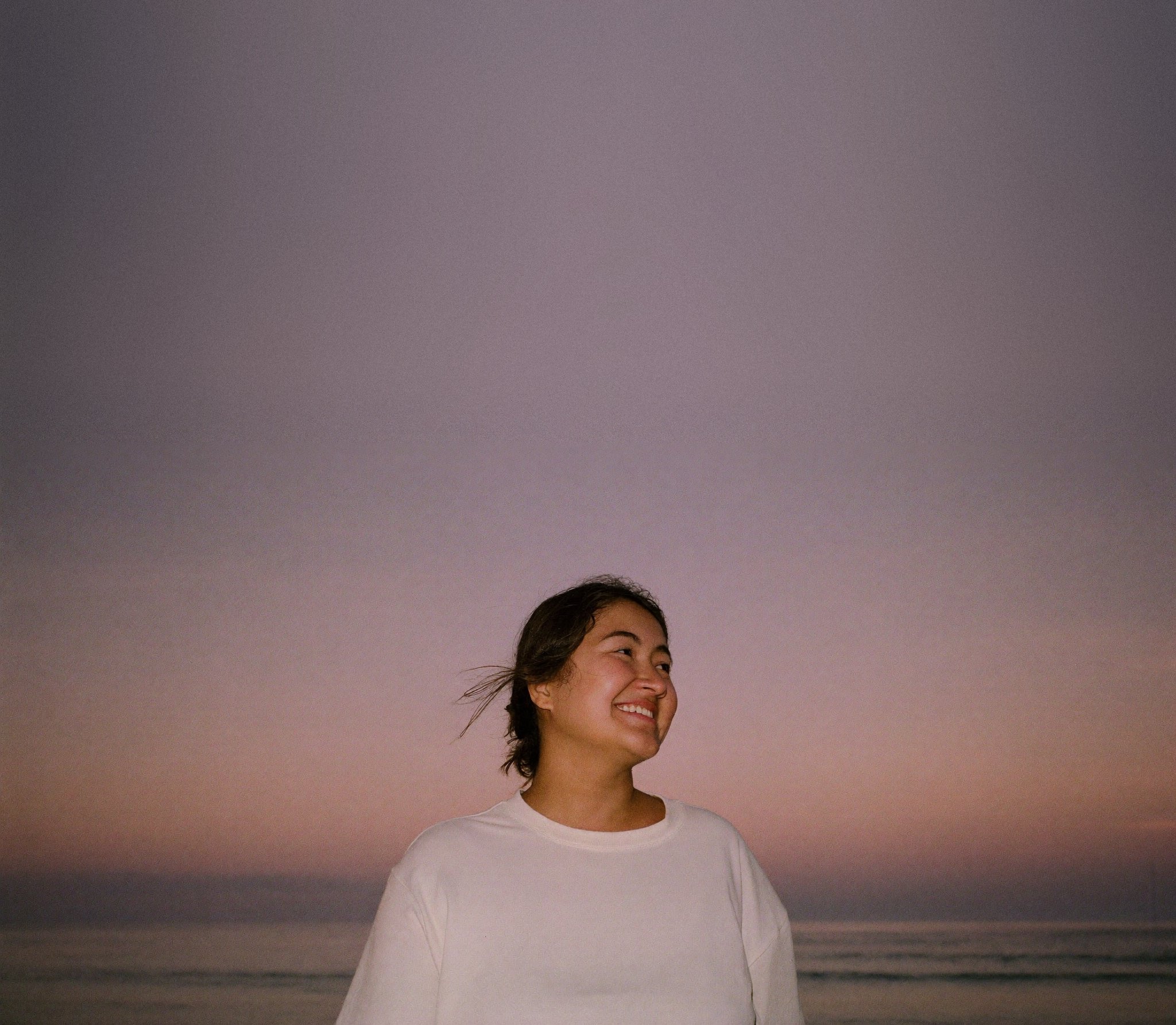 A woman laughing by the sea at dusk
